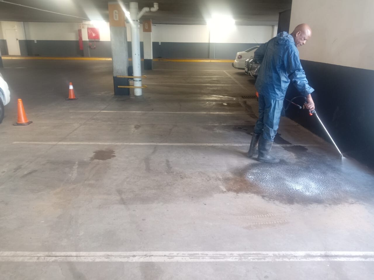 Sejo Cleaning Solutions operator in PPE pressure-washing a basement parkade floor